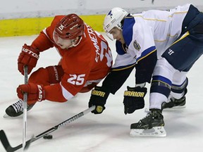 Red Wings centre Cory Emmerton, left, battles for the puck with Blues defenceman Kris Russell during NHL action in Detroit  Wednesday, Feb. 13, 2013. (AP Photo/Carlos Osorio)