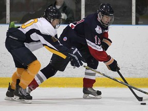 St. Joseph's Zach Galasso, left and Cardinal Carter's Austin Thompson battle for the puck during Game 1 of the Cullen Division championship Thursday, Feb. 28, 2013, at the WFCU Centre. The Lasers beat the Cougars 6-5 in double overtime. (DAN JANISSE/The Windsor Star)