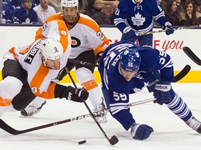 Toronto's Korbinian Holzer. right. and Philadelphia's Mike Knuble battle for the puck as Flyer Maxime Tabot looks on during the first period in Toronto Monday February 11, 2013.(THE CANADIAN PRESS/Chris Young)