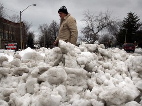 A pedestrian walks by a mound of snow on Giles Boulevard East in Windsor, Ont. on Feb. 27, 2013. (Nick Brancaccio / The Windsor Star)