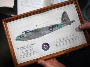 Tim Gillies holds a picture of what the De Havilland Mosquito bomber looked like during WW2 while at Canadian Historical Aircraft Association at Windsor International Airport, Saturday, March 9, 2013.  After nearly 15 years of sitting vertically, a reconstructed wingspan for the mosquito bomber is being turned horizontal before being eventually inserted into the fuselage of the aircraft. (DAX MELMER/The Windsor Star)