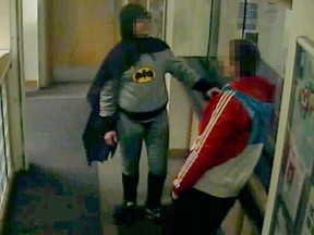 This handout image obtained from West Yorkshire Police on March 5, 2013 taken from closed circuit television footage captured at Trafalgar House Police Station in Bradford on February 25, 2013 shows a person dressed in a Batman costume handing over a crime suspect for arrest. A takeaway delivery man revealed on March 5, 2013 that he is the mysterious crime-fighter whose image went viral online after he walked into a British police station dressed as Batman and handed over a wanted man. Stan Worby, 39, sparked a wave of theories about his identity on Monday when police released a CCTV image of a man dressed as the comic book hero, delivering the suspect to a police station in Bradford, northern England.