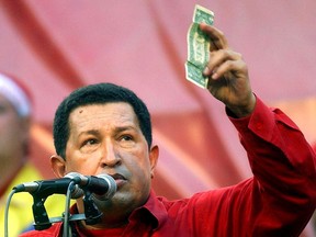 In this Jan. 23, 2005 photo, Venezuela's President Hugo Chavez holds up a U.S. dollar bill and challenges U.S. President George W. Bush to bet which of them will remain in power longer at a rally in Caracas, Venezuela. Venezuela's Vice President Nicolas Maduro announced that Chavez died on Tuesday, March 5, 2013, at age 58 after a nearly two-year bout with cancer. (AP Photo/Fernando Llano, File)