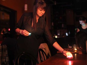 Lisa Patrick, a waitress at Chanoso's and Oishii restaurant in Windsor, Ont., places candles on tables as the restaurant turned out the lights for Earth Hour, Saturday, March 23, 2013.  (DAX MELMER/The Windsor Star)