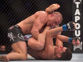 Georges St-Pierre, left, from Canada pins Nick Diaz from the United States to the canvas during their UFC 158 title fight in Montreal, Saturday, March 16, 2013. (THE CANADIAN PRESS/Graham Hughes)