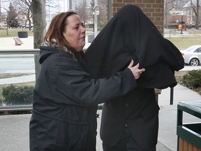 A woman leads Stan Laforge out of Superior Court in Windsor, Ont., Tuesday, March 19, 2013, after putting a coat over his face. Laforge, 26, is charged with sexual assault. (DAN JANISSE/The Windsor Star)