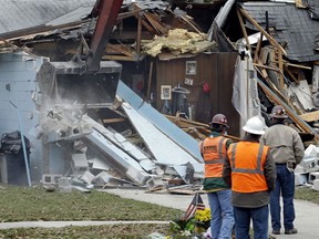 Demolition experts watch as the home of Jeff Bush, 37, is destroyed Sunday, March 3, 2013, in Seffner, Fla. The 20-foot-wide opening of the sinkhole was almost covered by the house, and rescuers said there were no signs of life since the hole opened Thursday night. (AP Photo/Chris O'Meara)