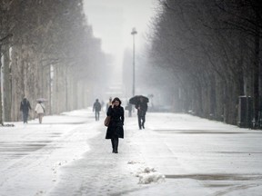 People walk in a street of Paris on March 12, 2013, during a heavy snow storm on France. More than 68,000 homes were without electricity in France and hundreds of people were trapped in their cars, officials and weather services said today. Twenty-six regions in northwest and northern France were put on orange alert because of heavy snowfalls, which Meteo France said were "remarkable for the season because of the expected quantity and length of time". AFP PHOTO / FRED DUFOUR