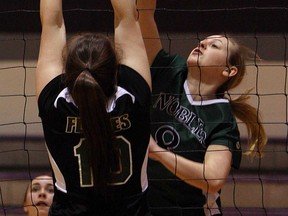 The Belle River Nobles Michaela Therrien spikes the ball as the Patrick Fogarty Flames Lexie North defends during OFSSA girls volleyball at Assumption high school in Windsor, Ont. on Monday, March 4, 2013.                   (TYLER BROWNBRIDGE / The Windsor Star)