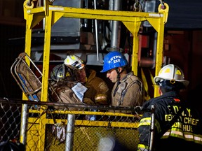 A worker, with black fire helmet at left inside a construction transport bucket, is rescued from an MTA subway construction project in New York early Wednesday, March 20, 2013 after being trapped up to his chest in debris for several hours. Fire officials say he is awake and conscious and is being evaluated at a local hospital. (AP Photo/Craig Ruttle)