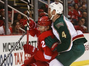 Detroit's Damien Brunner, left, is checked by Minnesota's Clayton Stoner at Joe Louis Arena. (Photo by Tom Szczerbowski/Getty Images)