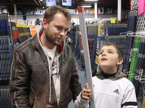 Dean Curtis and his son Clay check out hockey sticks, Thursday, March 21, 2013, at the Perani's Hockey World store in Windsor, Ont. The federal budget will include significant savings on hockey equipment.  (DAN JANISSE/The Windsor Star)