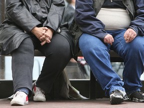 An obese man and woman sit on a bench in England. (Getty Images files)