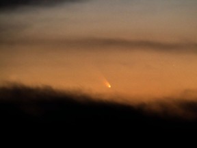 In this Sunday, March 10, 2013 photo taken with a 600-millimeter telephoto lens, comet Pan-STARRS appears between the clouds low in the western sky as seen from Harrells, N.C. The comet, which was closest to the sun on Sunday, is expected to become more easily visible to observers in the Northern Hemisphere during the coming week. (AP Photo/The Fayetteville Observer, Johnny Horne)