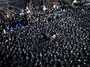 Members of the Satmar Orthodox Jewish community congregate for the funeral of two expectant parents who were killed in a car accident, Sunday, March 3, 2013, in the Brooklyn borough of New York. A driver struck the car the couple were riding in early Sunday morning, killing both parents while their baby, who was born prematurely, survived and is in critical condition. (AP Photo/John Minchillo)