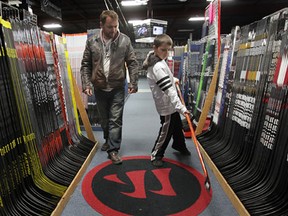 Dean Curtis and his son Clay check out hockey sticks, Thursday, March 21, 2013, at the Perani's Hockey World store in Windsor, Ont. The federal budget will include significant savings on hockey equipment.  (DAN JANISSE/The Windsor Star)