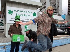 Frank Incitti does his best leprechaun impression by trying to click his heels as David Lenz, left,  Tom Lucier and Mike Lambros, behind, get fired up for their combined St. Patrick's Day outdoor party to be held in the parking lot beside Phog Lounge on University Avenue West at Victoria Street this weekend. (NICK BRANCACCIO / The Windsor Star)