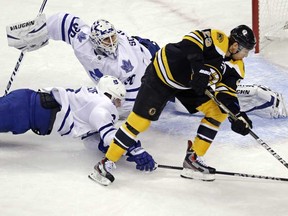 Maple Leafs defenceman Dion Phaneuf, bottom left, knocks the puck off the stick of Bruins centre Chris Kelly , right, as goalie Ben Scrivens looks back during the first period in Boston, Thursday, March 7, 2013. (AP Photo/Charles Krupa)