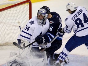 Maple Leafs goaltender James Reimer, left, is hit by Winnipeg's Andrew Ladd, centre, after being pushed into the net by Mikhail Grabovski in Winnipeg, Tuesday, March 12, 2013. (THE CANADIAN PRESS/Trevor Hagan)