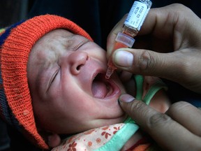 A Pakistani health worker administers polio vaccine drops to a child in Lahore, Pakistan on Wednesday, Dec. 19, 2012.