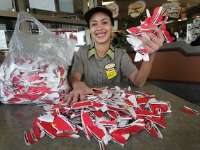 Tim Hortons employee Toni Picco, 30, holds up a fistful of winning Roll Up the Rim to Win rims at 5250 Walker Rd. in Windsor, Ont. on Mar. 26, 2013. (Dan Janisse / The Windsor Star)