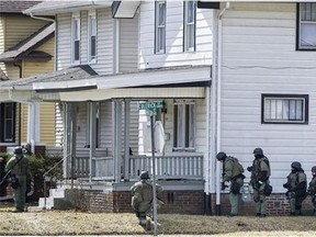 Armed officers surround a house March 20, 2013 in Fort Wayne, Ind., where police say a man suspected of killing a bus passenger earlier in the day was holding a 3-year-old child hostage.(Swikar Patel/Associated Press)