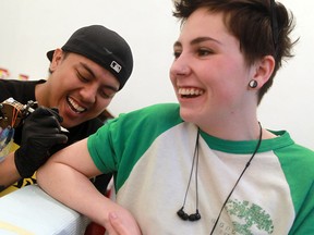 Windsorite Katie Whitehead (R) and tattoo artist Jon Jimenez share a laugh at Broken City Lab's Windsor-themed tattoo event on Mar. 7, 2013. (Tyler Brownbridge / The Windsor Star)