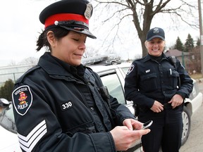 Sgt. Pam Mizuno (L) tweets with her cellphone while Const. Lindsay Lemming (R) looks on. Photographed at Lanspeary Park in Windsor, Ont. on Mar. 22, 2013. Regional police agencies were on Twitter throughout the day as a part of a social media campaign. (Tyler Brownbridge / The Windsor Star)
