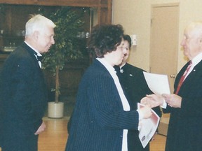 New Windsorite Hajrija Halilovic accepts The Canadian Charter of Rights and Freedoms from Eugene Whelan at the Caboto Club in Nov. 2002. Her husband, Ibrahim, left, looks on.