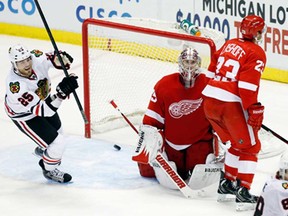 Chicago's Viktor Stalberg, left, celebrates a tying goal by Blackhawks teammate Patrick Kane, right, against Detroit goalie Jimmy Howard, center and defenceman Brian Lashoff Sunday, March 3, 2013 in Detroit. Kane was the only player to score during a shootout to defeat the Wings 2-1. (AP Photo/Duane Burleson)