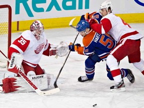 Red Wings goalie Jimmy Howard, left, makes the save on Edmonton's Teemu Hartikainen, centre, as Jakub Kindl defends during the first period in Edmonton, Alta., on Friday March 15, 2013. The Wings won 3-2 in OT. (THE CANADIAN PRESS/Jason Franson.)