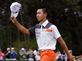 China's Guan Tianlang waves his cap after putting out on the 18th hole during the fourth round of the Masters golf tournament Sunday in Augusta, Ga. (AP Photo/David J. Phillip)