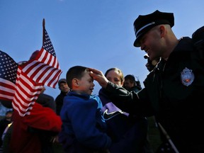 Watertown Police officer Brandon O'Neill (R) touches the head of a young boy during a candlelight vigil at Victory Park on April 20, 2013 in Watertown, Massachusetts. (Photo by Jared Wickerham/Getty Images)
