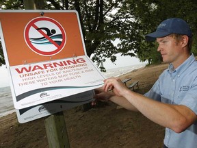 In this file photo, Nathan Gignac, a conservation area technician with ERCA, puts up a sign warning swimmers the water is unsafe for swimming due to high levels of bacteria, at Holiday Beach, Thursday, July 5, 2012.   (DAX MELMER/The Windsor Star).