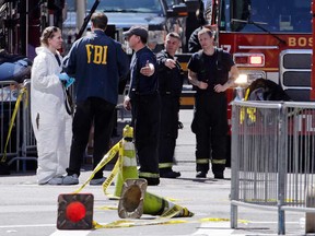 Boston firefighters, right, talk with FBI agents and a crime scene photographer at the scene of Monday's Boston Marathon explosions, which killed at least three and injured more than 140, in Boston, Tuesday, April 16, 2013. The bombs that blew up seconds apart near the finish line left the streets spattered with blood and glass, and gaping questions of who chose to attack at the Boston Marathon and why. (AP Photo/Charles Krupa)