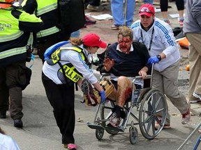 Medical workers aid an injured man at the 2013 Boston Marathon following an explosion in Boston, Monday, April 15, 2013. Two bombs exploded near the finish of the Boston Marathon on Monday, killing at least two people, injuring at least 22 others and sending authorities rushing to aid wounded spectators. (AP Photo/The Boston Globe, David L. Ryan)