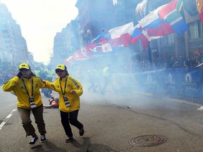 People react to an explosion at the 2013 Boston Marathon in Boston, Monday, April 15, 2013. Two explosions shattered the euphoria of the Boston Marathon finish line on Monday, sending authorities out on the course to carry off the injured while the stragglers were rerouted away from the smoking site of the blasts. (AP Photo/The Boston Globe, John Tlumacki)