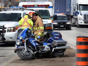 Tecumseh firefighters check damage to a Harley-Davidson motorcycle after the driver lost control while switching lanes on Highway 3 east of Howard Avenue, Thursday April 17, 2013. Essex-Windsor EMS paramedics took the driver to hospital.  (NICK BRANCACCIO/The Windsor Star)