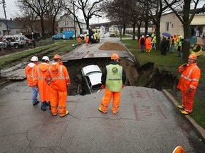 Workers prepare to pull a truck from a sinkhole that opened up on a residential street in the South Deering neighborhood on April 18, 2013 in Chicago, Illinois. The driver of the truck was hospitalized after driving into the 15-feet-deep hole while on his way to work. Two other vehicles were also swallowed by the sinkhole. (Scott Olson/Getty Images)