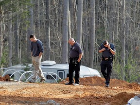 A man, left, walks with police investigators Monday, April 8, 2013, around the scene of a collapsed construction site where two children died when the dirt walls collapsed Sunday on Cedarbrook Court in Stanley, N.C. (AP Photo/Bob Leverone)