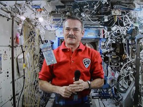Astronaut Chris Hadfield poses for a photo with a new polymer $5 bank note on Tuesday, April 30, 2013. (THE CANADIAN PRESS/Sean Kilpatrick)