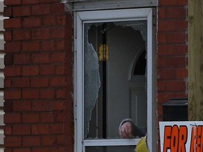 An unidentified woman cleans broken glass from the front door of a home at 818 Langlois Ave. in Windsor, Ont. after shots were fired at the home in the early morning, Saturday, April 13, 2013.  No one was injured in the shooting.  (DAX MELMER/The Windsor Star)