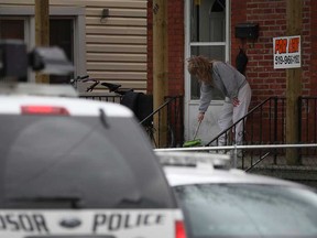 An unidentified woman cleans broken glass from the front porch of a home at 818 Langlois Ave. in Windsor, Ont. after shots were fired at the home in the early morning, Saturday, April 13, 2013.  No one was injured in the shooting.  (DAX MELMER/The Windsor Star)