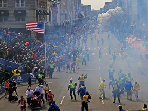 People react as an explosion goes off near the finish line of the 2013 Boston Marathon in Boston, Monday, April 15, 2013. Two explosions went off at the Boston Marathon finish line on Monday, sending authorities out on the course to carry off the injured while the stragglers were rerouted away from the smoking site of the blasts. (AP Photo/The Boston Globe, David L Ryan)