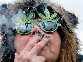 The Peace Tower is reflected in the sunglasses of a woman smoking a joint at the Fill the Hill marijuana rally on Parliament HIll in Ottawa on Saturday, April 20, 2013. THE CANADIAN PRESS/Justin Tang