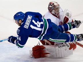 Vancouver's Alex Burrows, left, trips over Detroit goalie Jimmy Howard and loses control of the puck on a breakaway during the first period Saturday in Vancouver. (THE CANADIAN PRESS/Darryl Dyck)