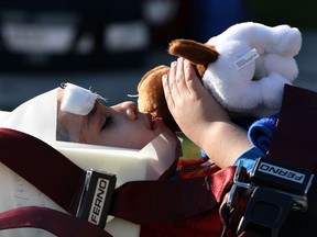 A young accident victim is comforted with a stuff animal as being rescued by Essex-Windsor EMS paramedics and Windsor firefighters on Milloy Street following a two vehicle collision where a Jeep TJ lost control and hit a tree and fence, Monday April 22, 2013. (NICK BRANCACCIO/The Windsor Star)