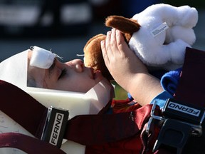 A young accident victim is conforted with a stuff animal as being rescued by Essex-Windsor EMS paramedics and Windsor firefighters on Milloy Street following a two vehicle collsion where a Jeep TJ lost control and hit a tree and fence, Monday April 22, 2013. (NICK BRANCACCIO/The Windsor Star)