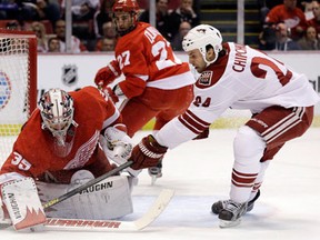 Detroit goalie Jimmy Howard, left, stops a shot by Phoenix forward Kyle Chipchura with Kyle Quincey in the background. (AP Photo/Paul Sancya)