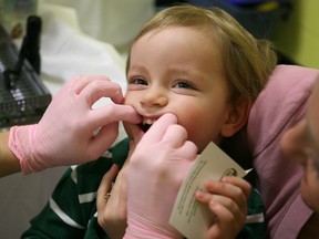 Alexander Wacheski, 2, being held by his mother, Kelly Wacheski, has his teeth examined by Karen Kelly, left, a dental hygienist at the Windsor Essex County Health Unit on April 17, 2013.  (DAX MELMER/The Windsor Star
